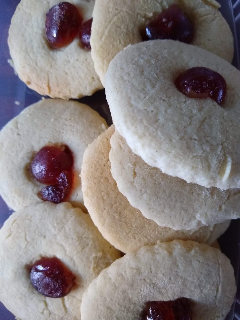 A container of rice biscuits with cherries on the top.