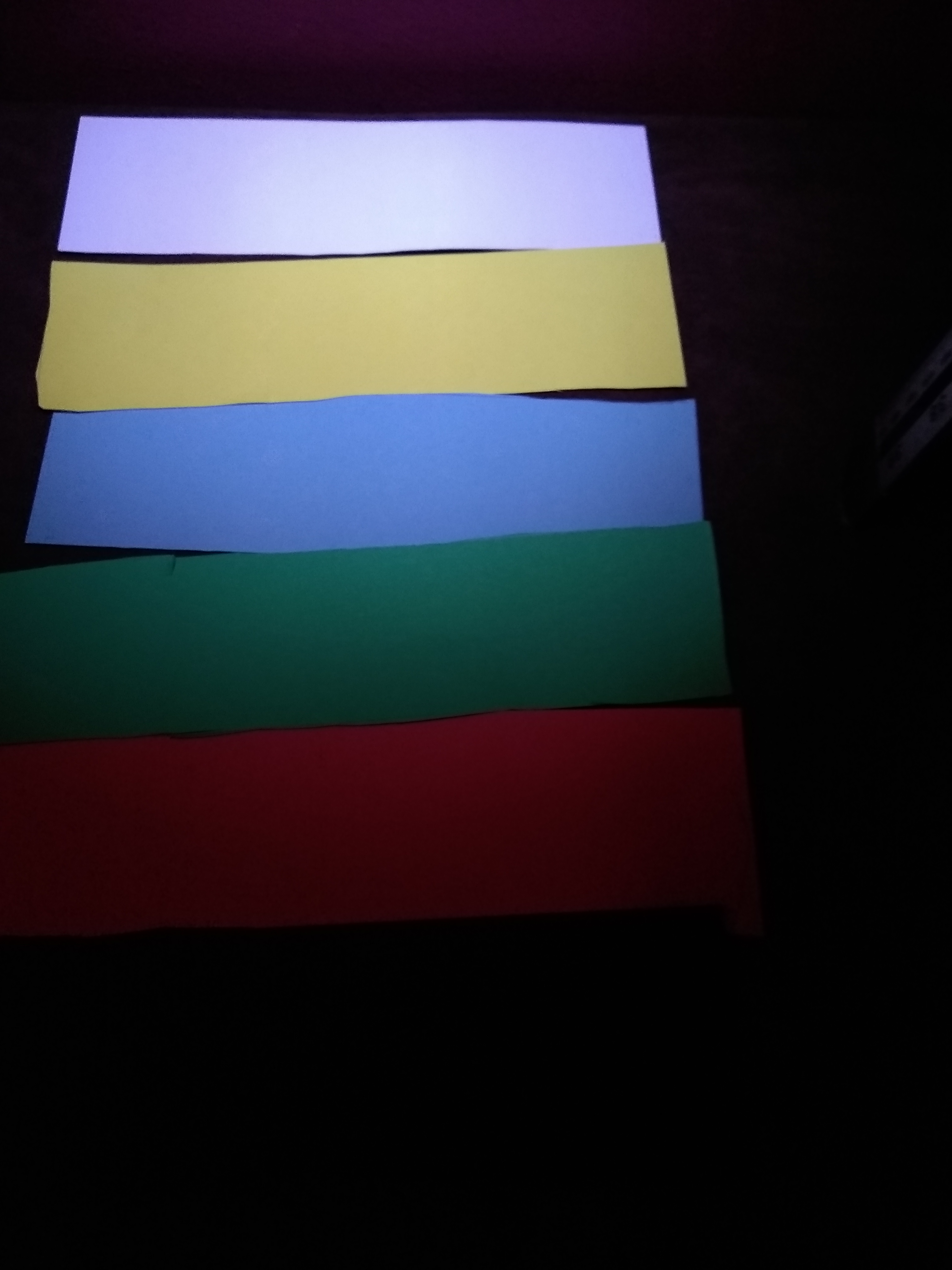 A photograph showing the card lined up in order, from brightest to darkest: white, yellow, blue, green, red and black.