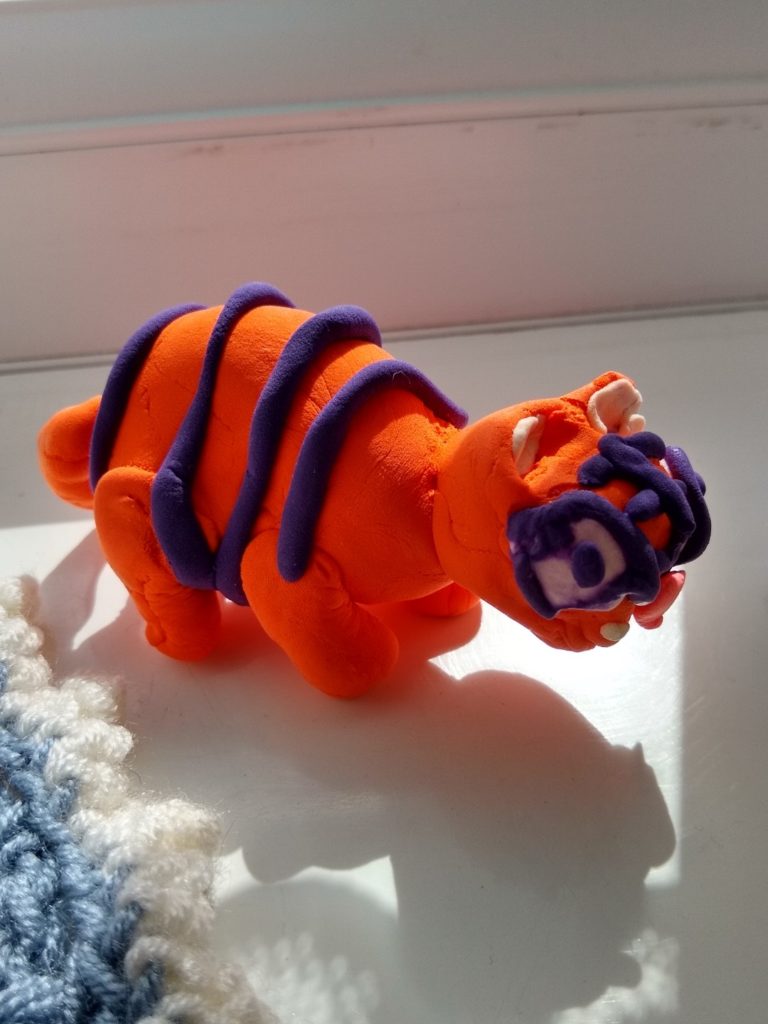 A photo of our orange clay model Siberian tiger with dark purple eyes and stripes.