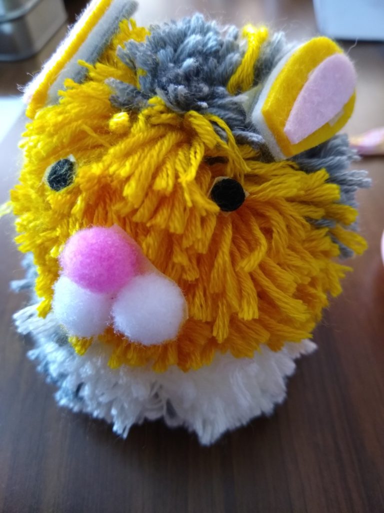 A photo showing the finished bunny with its grey, cream and yellow ears; black eyes; and pink and white nose. 