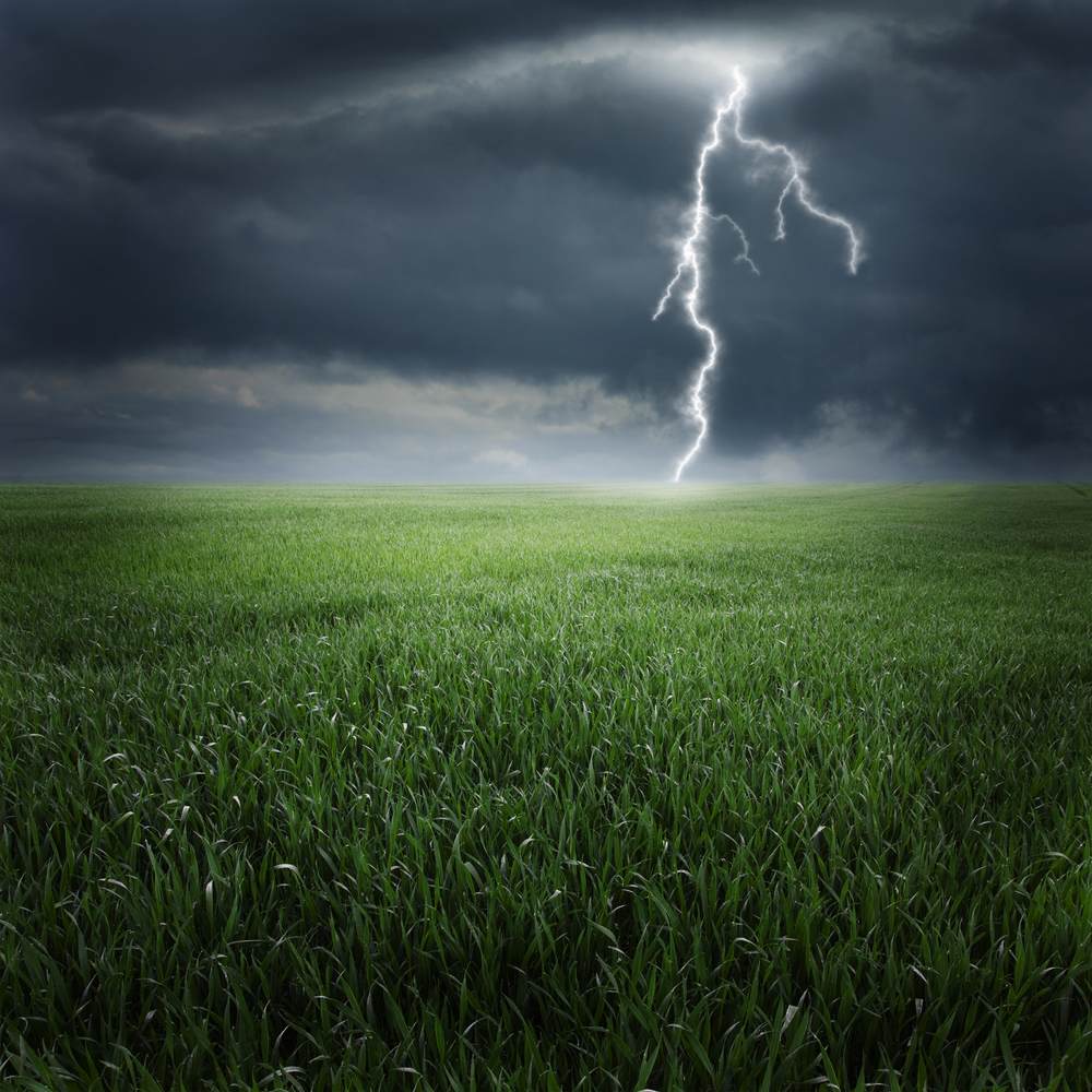 A photo of a cloud-to-ground strike on a green field.