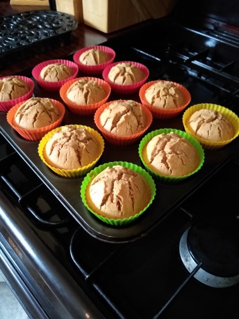 A photo of our delicious muffins in green, yellow, red and orange bun cases.