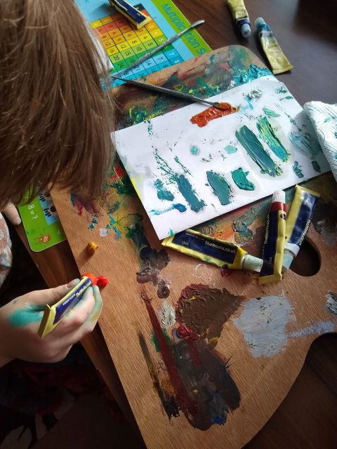 A photo showing me mixing oil paints to make greens and reds, on paper and a board.