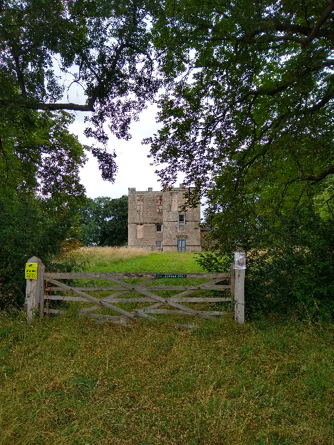 A photo of the ruins of a grand castle-style house behind a gate.