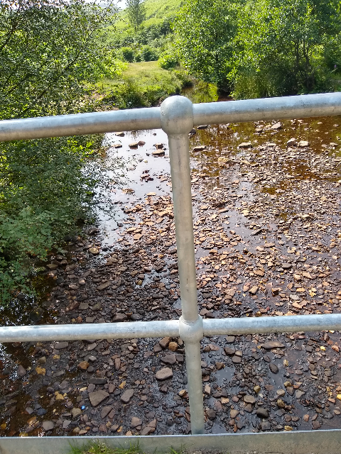 View of a stony stream from a metal bridge.