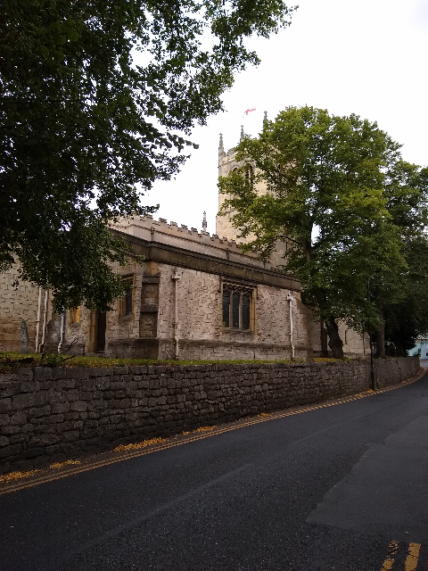 A photo of a stone-built church with a square tower and the St George's flag flying on top.