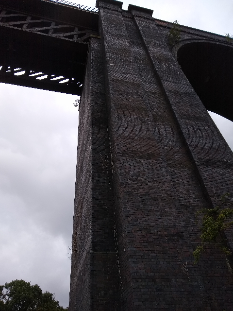 A photo looking up one of the pillars of the viaduct. At the top left is the iron part and on the right is the start of a brick arch.