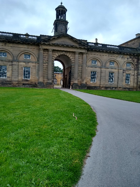 A photo of a large stone building with a large arched entrance leading into a courtyard.